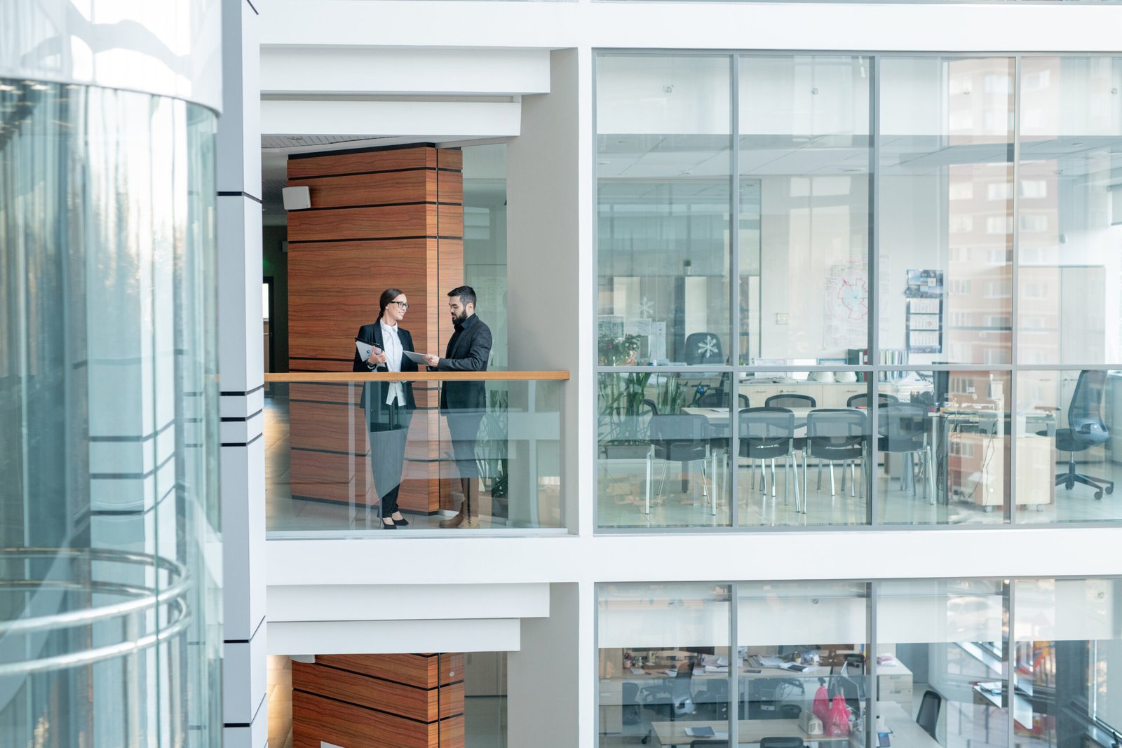 Young office workers standing on balcony of business center and sharing ideas for new project